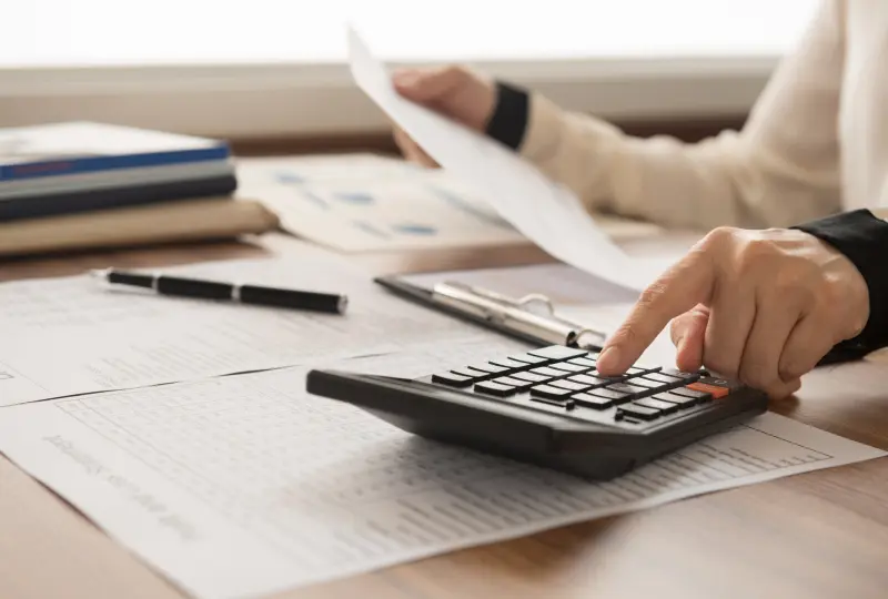 Person using calculator with financial documents.